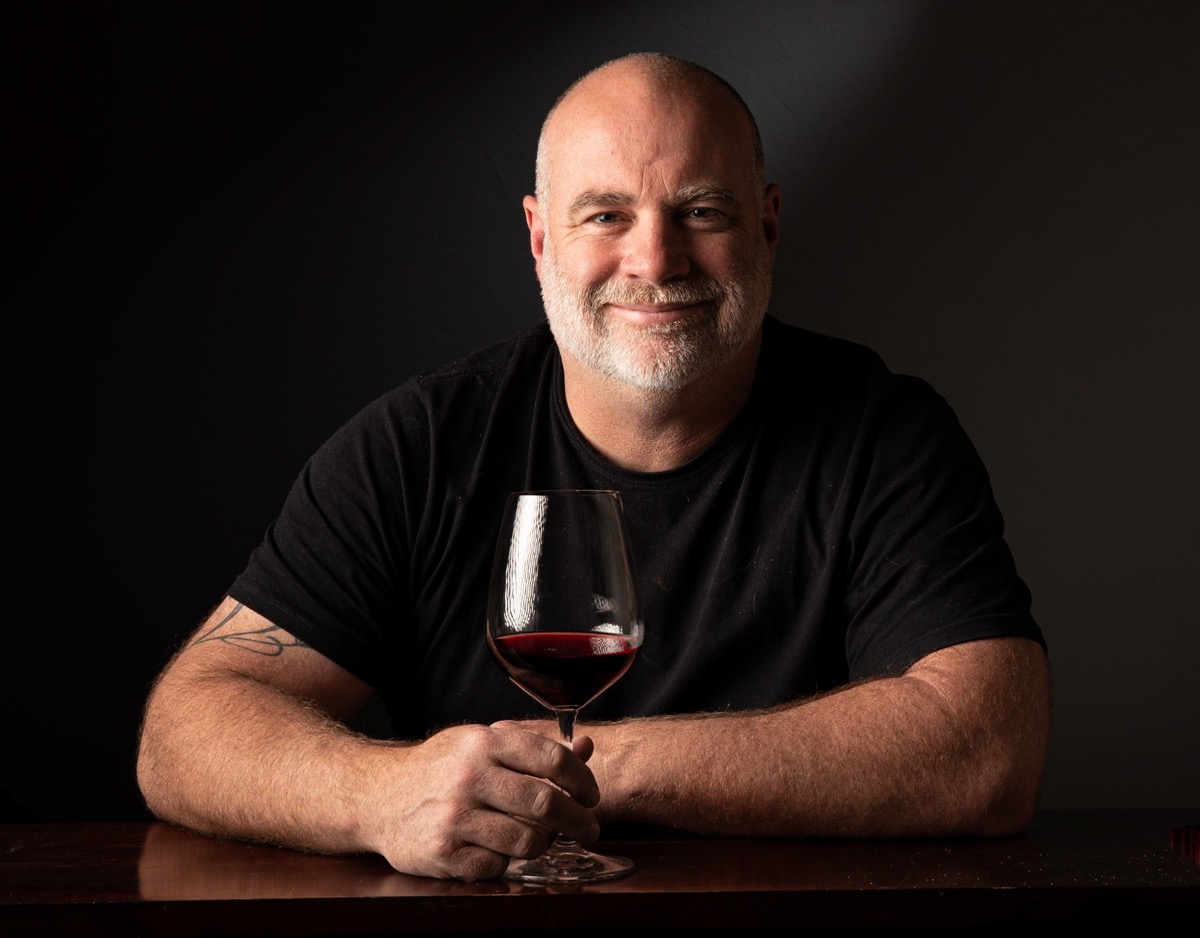 Tim White holding a glass of red wine